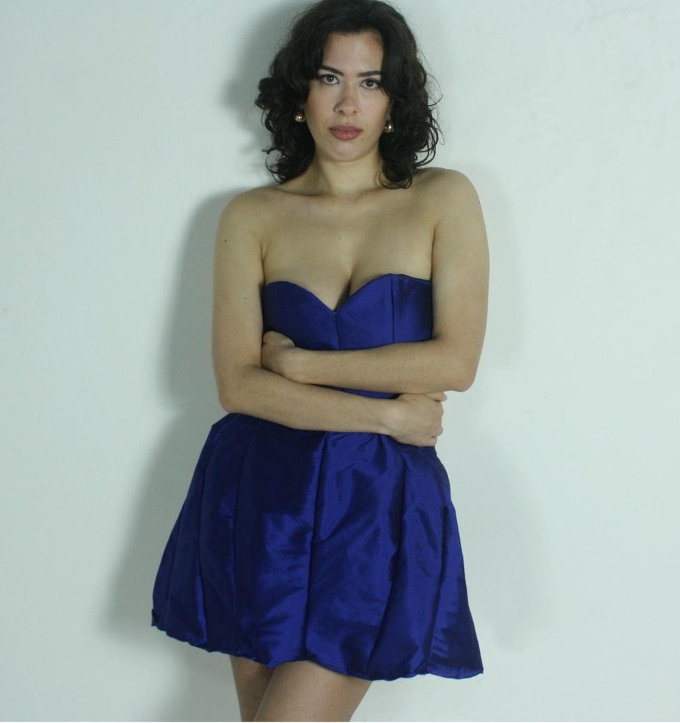 Modelo com vestido azul royal encostada na parede