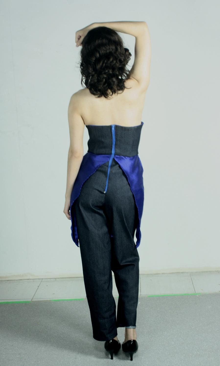 Modelo com macacão de jeans e sobressaia azul, mãos na cintura